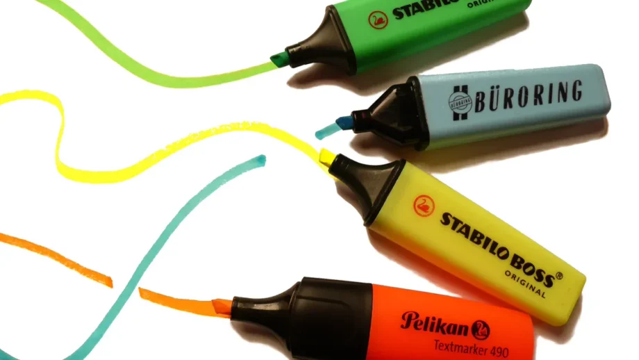 Bright highlighter pens and markers arranged on paper for designing a concert poster