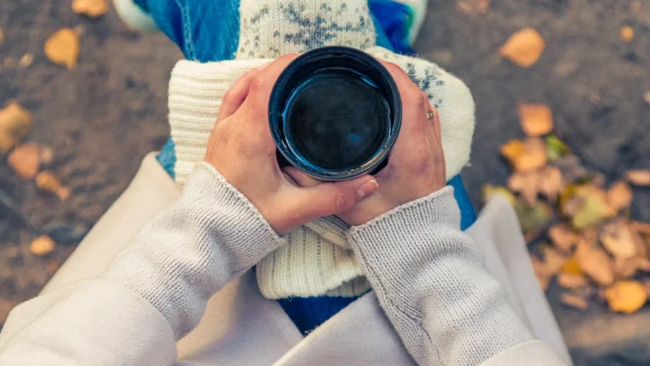 Steaming hot coffee mug surrounded by colorful autumn leaves setting a cozy television atmosphere