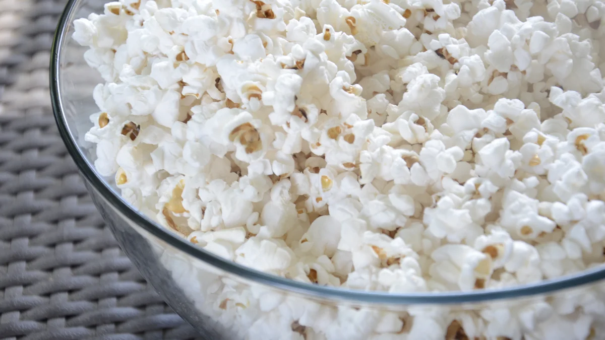 Popcorn bowl beside remote for comfort tv watching Popcorn in a bowl next to a television remote on a table during a comfort show watch