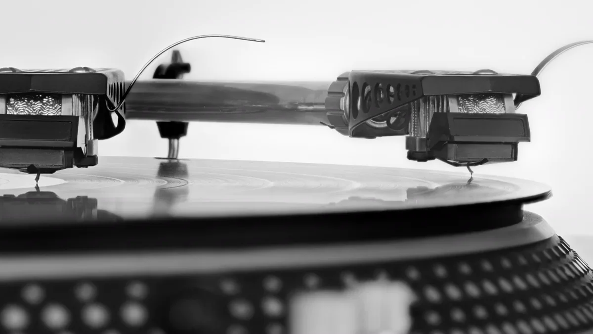 Turntable stylus needle tracking along black vinyl grooves on a spinning record